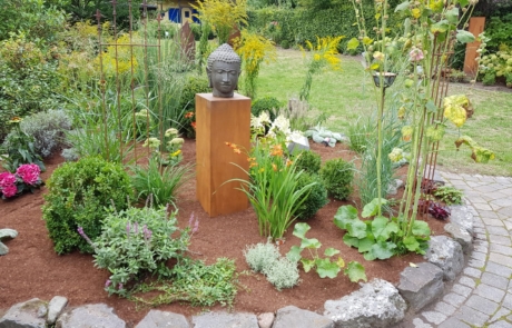 Gestaltetes Beet mit Blumen und Gartenaccesoirs